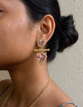 GUL floral drop earring worn on an ear, featuring pink flower motifs, gold-tone borders and a horizontal bar.