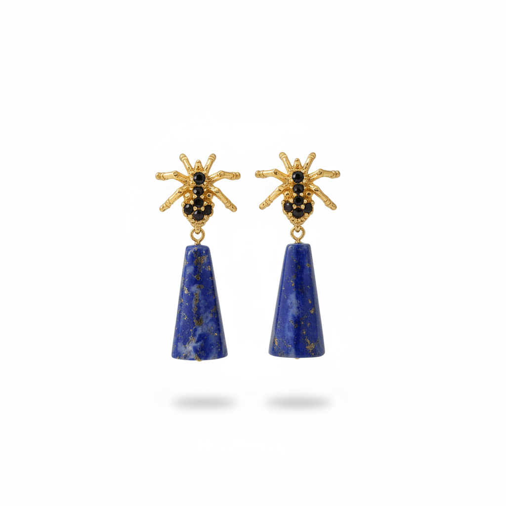 Spider Lapis Earrings with blue lapis drops and gold-tone spider studs, displayed on a sunlit grey surface.
